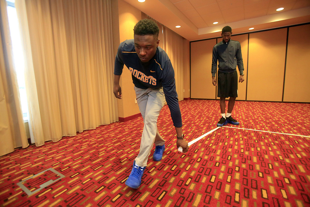 Head managers Deshaun Cole (left) and Brandon Jackson tape markings similar to a basketball court so the team can walk through plays at the hotel prior to the game in Muncie, Ind. The arena was unavailable due to another Ball State team needing it, so the team had to make do in the ballroom at the hotel.  (Kurt Steiss / The Blade)