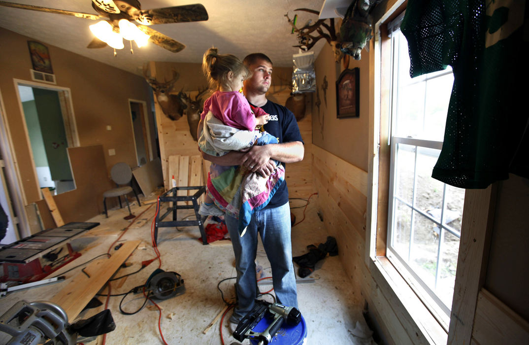 General News - 1st place - John Lawhorn, of Roxabell, takes a break from rebuilding the flooded interior of his house, to hold his daughter Grace. A levee broke on a branch of Little Creek flooding his property. (Jeff Hinckley / The Columbus Dispatch)