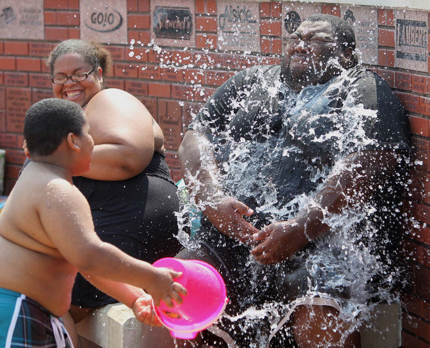 Feature - 3rd placeMarlina Fleming and her husband Jeremiah of Akron get doused with a bucket of water from their son Julian, 6, as they spend the afternoon cooling off at the Interactive Water Fountain at Falls River Square in Cuyahoga Falls.  (Karen Schiely / Akron Beacon Journal)