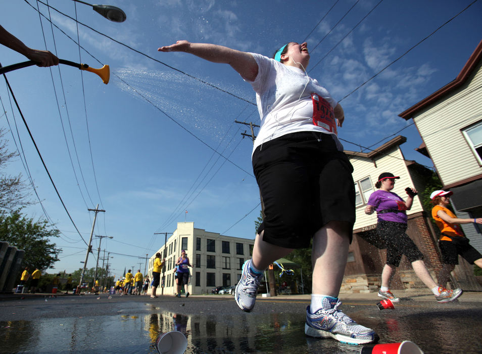 Sports Feature - 1st placeSarah Wolfe, from Canton, glides through the cool water of a hand-held sprinkler near mile marker nine along Scranton Road near Starkweather Avenue  during the 36th annual Rite Aid Cleveland Marathon. (Lisa DeJong / The Plain Dealer)
