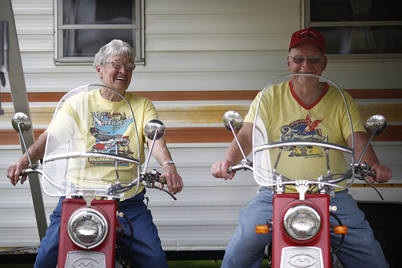 Portrait - HM - John Fairchild, 83, and his wife Beverly, 81, of Shelby pose for a photograph on their 1960s Cushman Silver Eagle scooters in front of their camper during the 20th annual Mid-Ohio Classic Scooters Show and Swap Meet at Pastime Park in Plain City. The couple has been riding Cushman's since 1965 and they have been coming to the swap meet every year for a number of years.  (Eamon Queeney / The Columbus Dispatch)