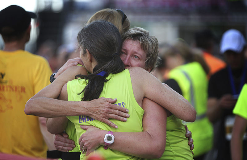 Sports Feature - HM - Robin Day, Kathy Hammel and Staci Hearth, of Bedford, Ind., embrace after competing in the Flying Pig 5K. "We ran in honor of our friend and trainer, Ken Barnes, who passed away suddenly a few weeks ago. We've all been training together for awhile now," said Hammel.  (Amanda Rossmann / Cincinnati Enquirer)