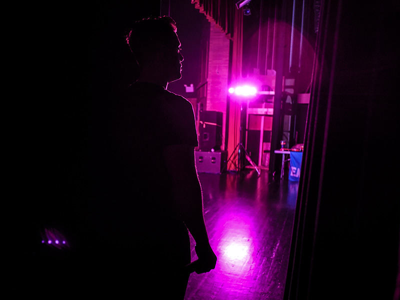 Story - 3rd place - Ennio Emmanuel waits to retake the stage during a performance at Clay High School in Oregon.  The foreign language department at the school hosted the singer who promotes the importance of learning a second language. (Andy Morrison / The (Toledo) Blade)