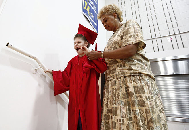 Portrait - 3rd place - The Franklin County Board of Developmental Disabilities held a graduation ceremony for the Class of 2016 at West Central School in Columbus. Graduate Athena Smetanko, 21, of Columbus, is assisted onto the stage by instructor assistant Patsy Gayle to receive her diploma. (Fred Squillante / The Columbus Dispatch)