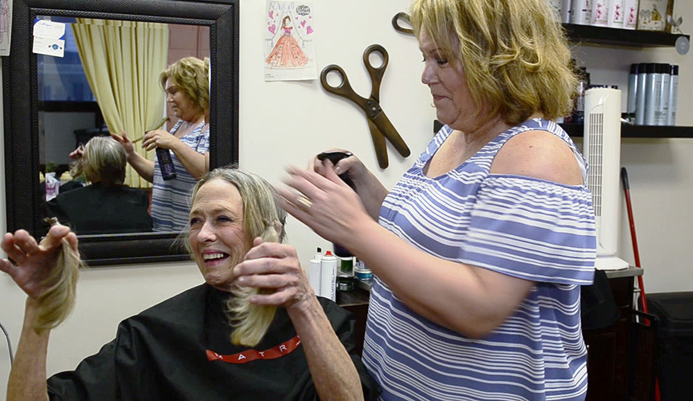Feature - 1st place - Patti Tucker holds up her hair she will donate. "Look at it all. That's my whole head," she says, using humor to lighten the pain and gravity of dealing with cancer.  (Molly Corfman / The News-Messenger)