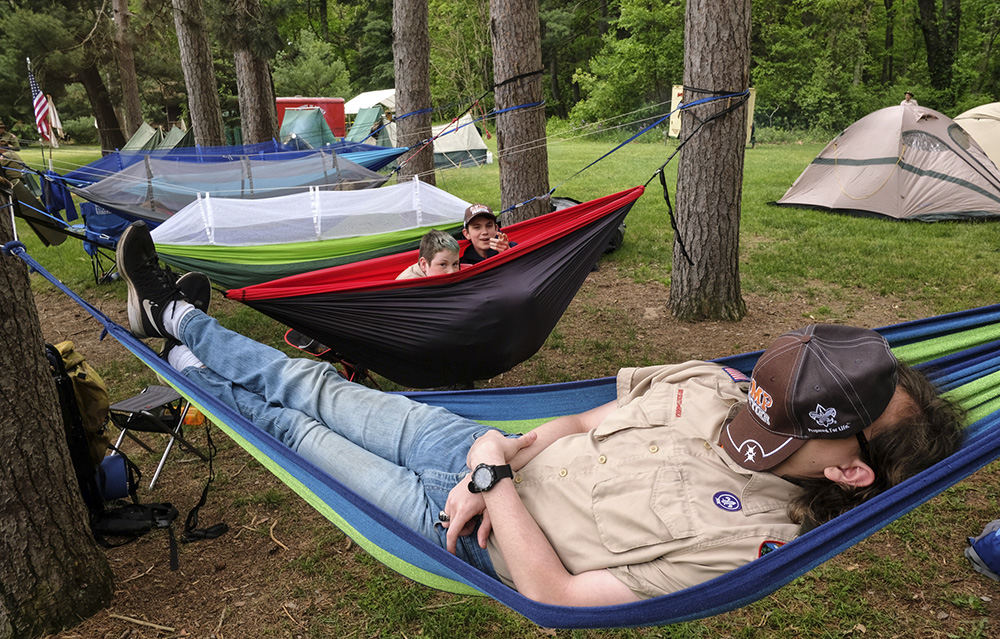    Feature - HM - Boy Scout Josh Burton of Sylvania rests  in a hammock as fellow scouts Ben Seal-Roth and Carter Rippel laugh at him during the 100th anniversary celebration at Camp Miakonda in Toledo.  (Jeremy Wadsworth / The (Toledo) Blade)