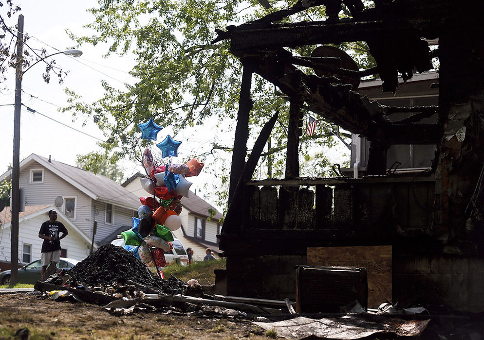 General News - 2nd place - A man examines fire damage while a memorial grows outside 693 Fultz Street in Akron. A fire broke out at the home on Monday killing five children and 2 adults. (Leah Klafczynski / Akron Beacon Journal)