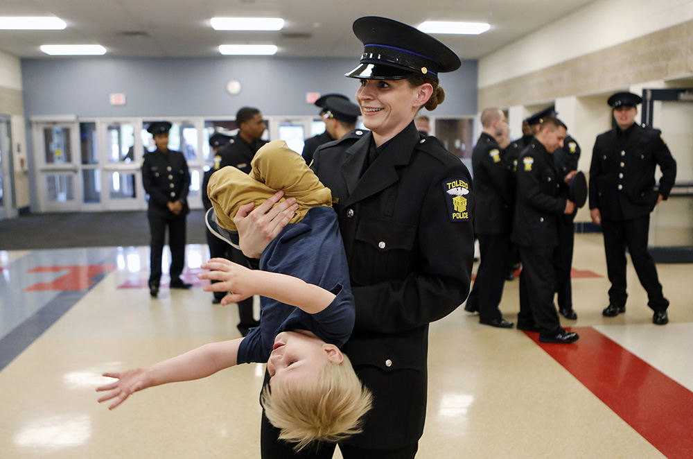 General News - HM - Toledo Police Cadet Taylor Dungjen apprehends her son Milan, before the 63rd Toledo Police Academy graduation ceremony at Bowsher High School. Ms. Dungjen is one of 25 new police officers for the city.  (Andy Morrison / The (Toledo) Blade)