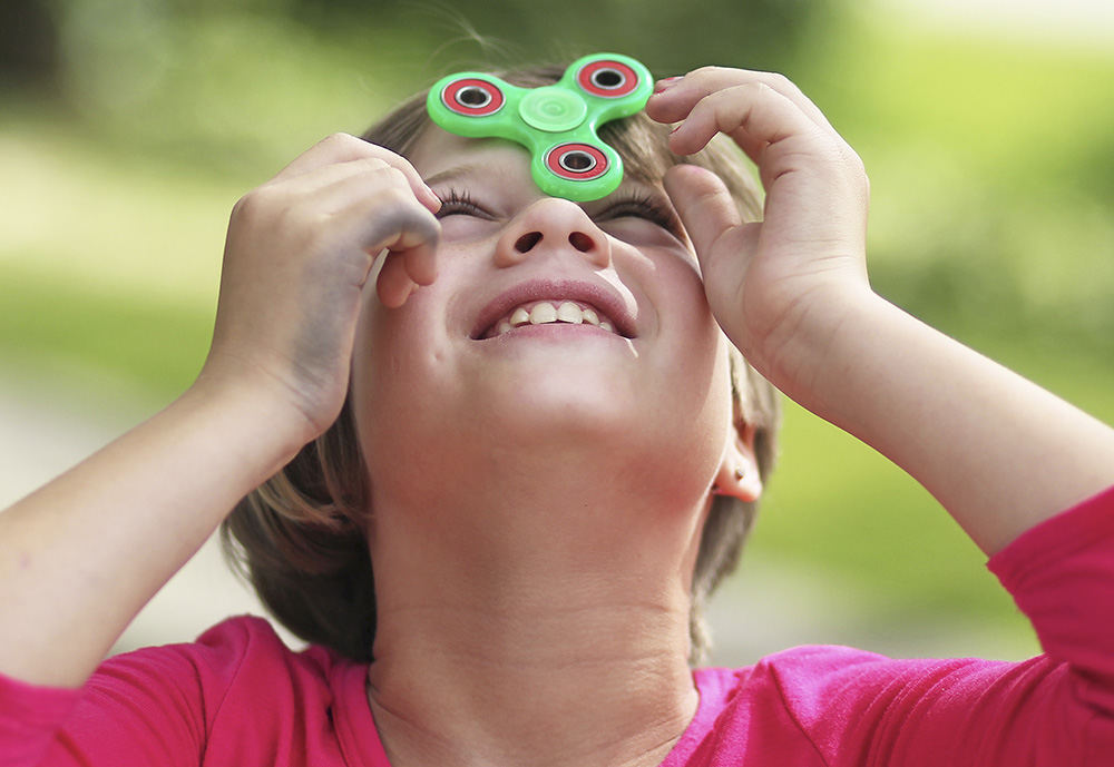Portrait - HM - Maddie Luecke, 9, balances a spinner on her head in her driveway in Copley. Spinners are currently all the rage among kids. (Leah Klafczynski / Akron Beacon Journal)