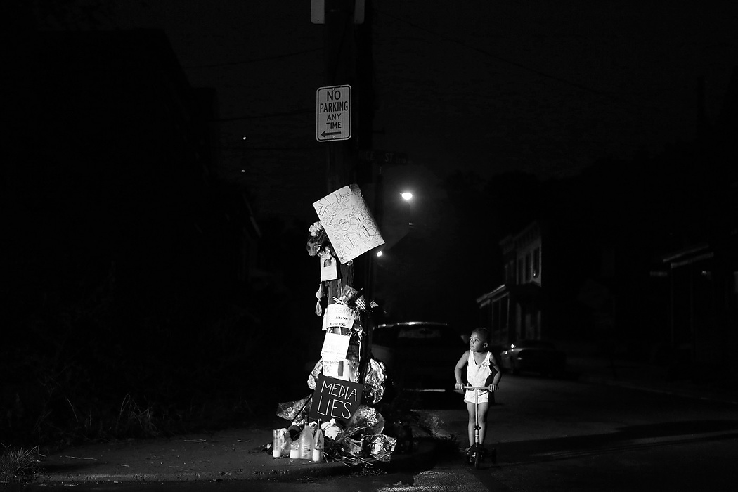 First Place, News Picture Story - Carrie Cochran / Cincinnati EnquirerNoel Mack, 4, who lives across the street from the site where Samuel DuBose was shot and killed, rides her scooter passed the makeshift memorial Wednesday night. Her mother didn't know DuBose, but says she lights the candles of the memorial every night. DuBose was unarmed when he was shot and killed by University of Cincinnati police officer Ray Tensing during a traffic stop on July 19. 