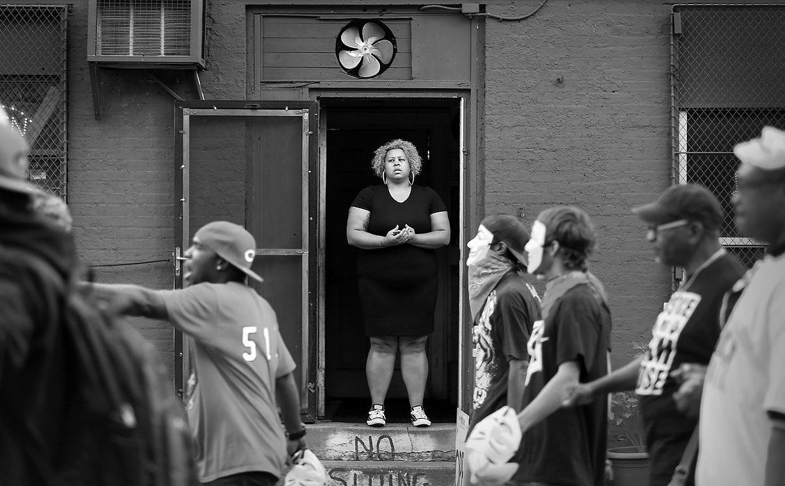 First Place, Photographer of the Year - Large Market - Carrie Cochran / Cincinnati EnquirerA bystander on Vine Street watches marchers head to the spot where Samuel DuBose was shot and killed by a UC police officer in July. A rally with other families who had loved ones also killed by police, including Samantha Ramsey and John Crawford participated in the march.