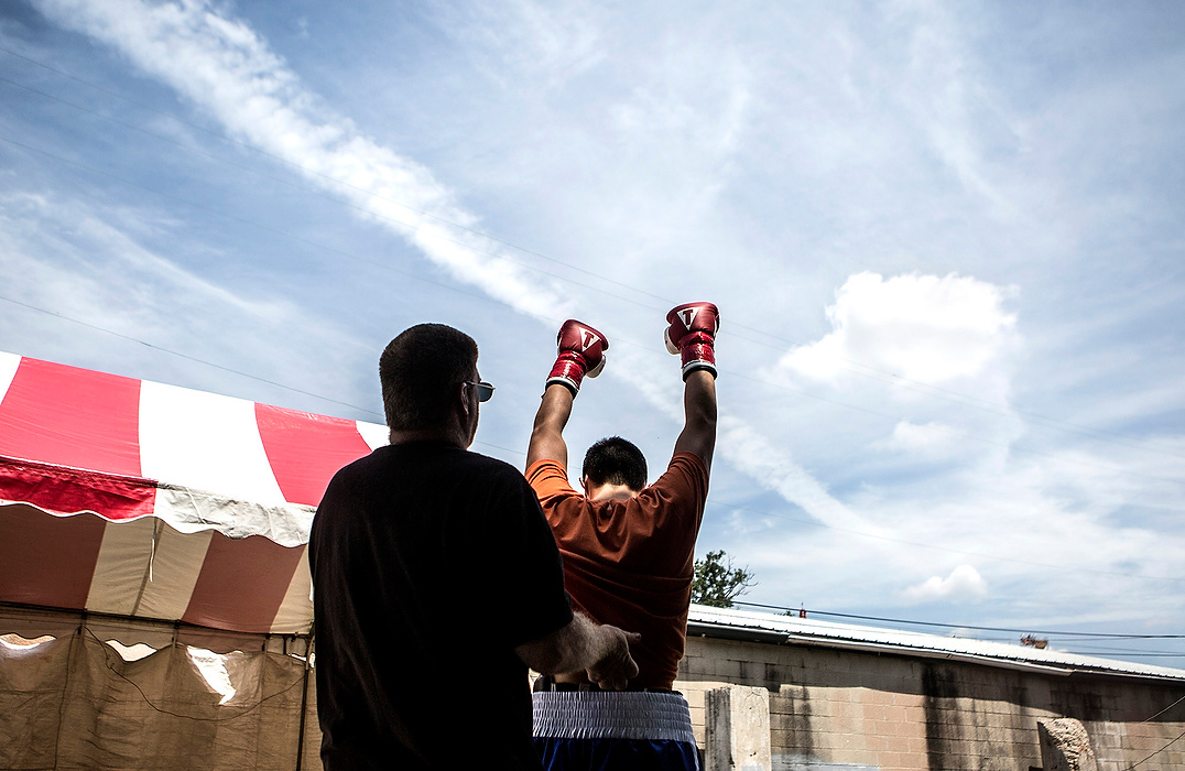 First Place, Photographer of the Year - Small Market - Jessica Phelps / Newark AdvocateMiles Delmindo is helped by his coach, Matt Voltolini, just before taking the ring at his debut professional boxing match. The fight, which Delmindo won, was fought under the hot sun at the Franklin County Fairgrounds. 