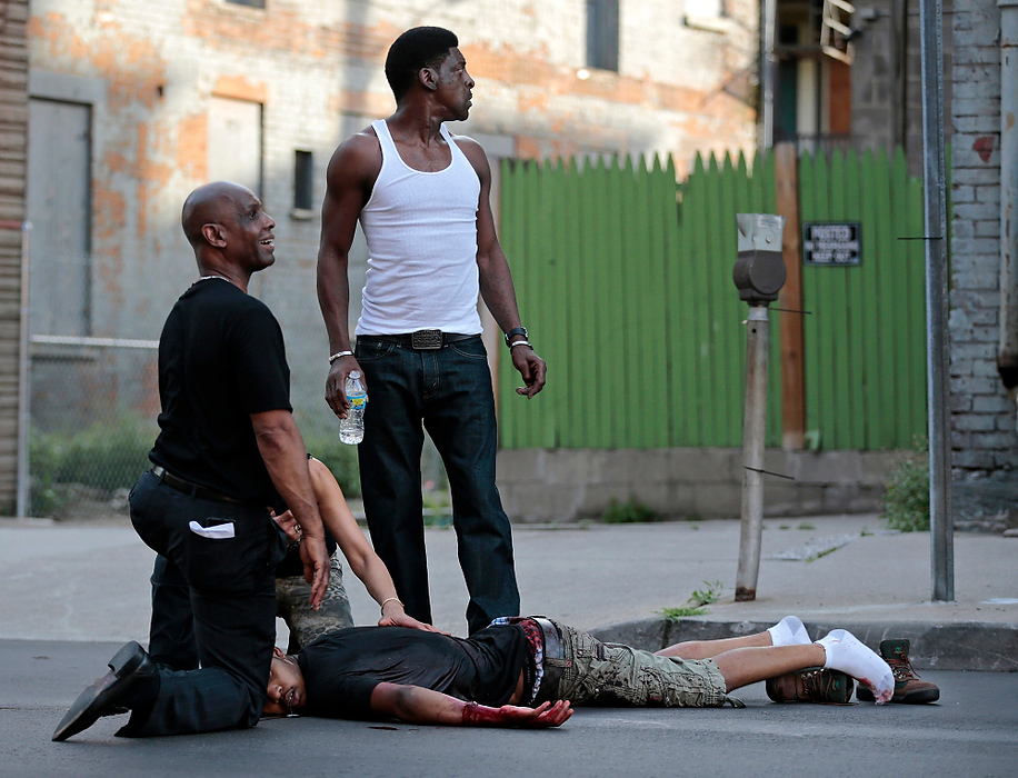 Second Place, Spot News - Large Market - Sam Greene / Cincinnati EnquirerState Senator Cecil Thomas, left, and bystanders look for help as they to tend to a 19-year-old shooting victim across from Findlay Market, where has was shot during three-person shootout in the Over-the-Rhine neighborhood of Cincinnati. The victim was transported to the hospital where he died of his injuries. Thomas was in the neighborhood as he was taking part in peace march through the neighborhood just moments before the gunfire. 
