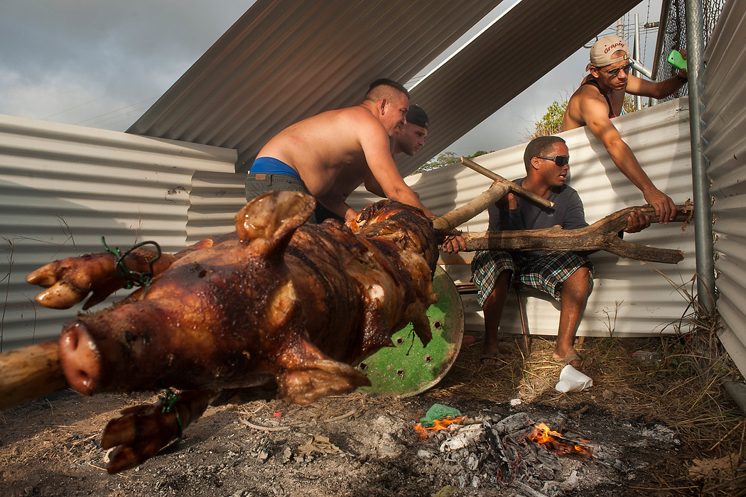 , Student Photographer of the Year - Eli C. Hiller / Ohio UniversityA group of Cuban men adjust a makeshift spit as they roast a pig along the fence of a shelter. The act of slow-roasting a pig is an annual tradition in Cuba to celebrate the arrival of a new year. 