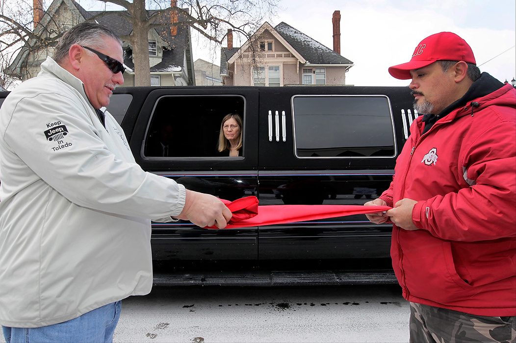First Place, Team Picture Story - Jetta Fraser / The (Toledo) BladeUAW Local 12 members and USMC veterans Jim Roe, of Temperance, Michigan, left, and Mario Duran, of Millbury, fold the flag of the United States Marine Corps before giving it to Sandra Drabik, widow of D. Michael Collins, in limousine. The funeral cortege stopped outside of the local hall to enable members to give Ms. Drabik, the flag.  Collins was a Marine.