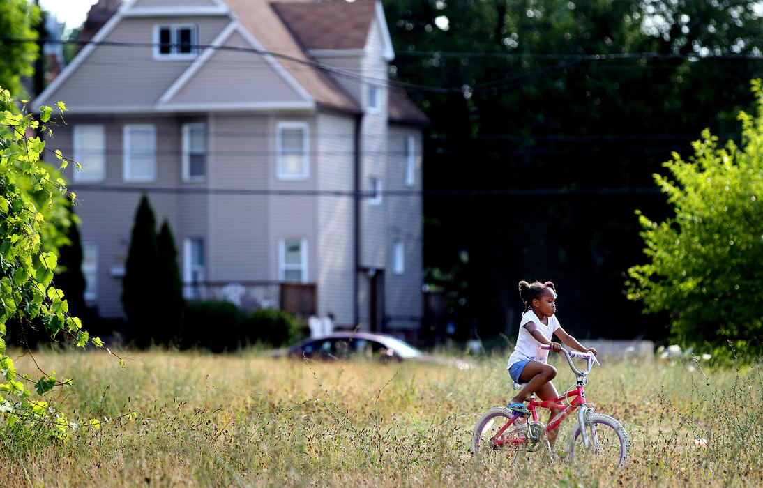 Award of Excellence, Ohio Understanding Award - Lisa DeJong  / The Plain DealerD'Zier Coleman, 5, rides her bike on a well-traveled dirt path through a vacant lot near the corner of Hough Avenue and E. 90th Street. Coleman rides her bike from her house to her grandmother's home often. Vacant lots are peppered along Hough Avenue where many building were burnt down in the Hough riots in 1966. 