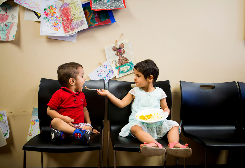 Second Place, James R. Gordon Ohio Understanding Award - Meg Vogel / Cincinnati EnquirerGhalia Alhamoud feeds hummus to her her brother, Yousif, at an Eid al-Fitr celebration at the Catholic Charities offices on Thursday, July 7, 2016. Eid al-Fitr marks the end of Ramadan fasting.