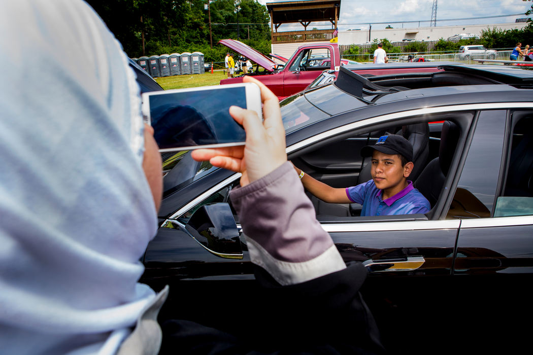 Second Place, James R. Gordon Ohio Understanding Award - Meg Vogel / Cincinnati EnquirerHasan Alhamoud poses for a photo in a Tesla car at the Immaculate Heart of Mary parish festival Sunday, July 17, 2016.
