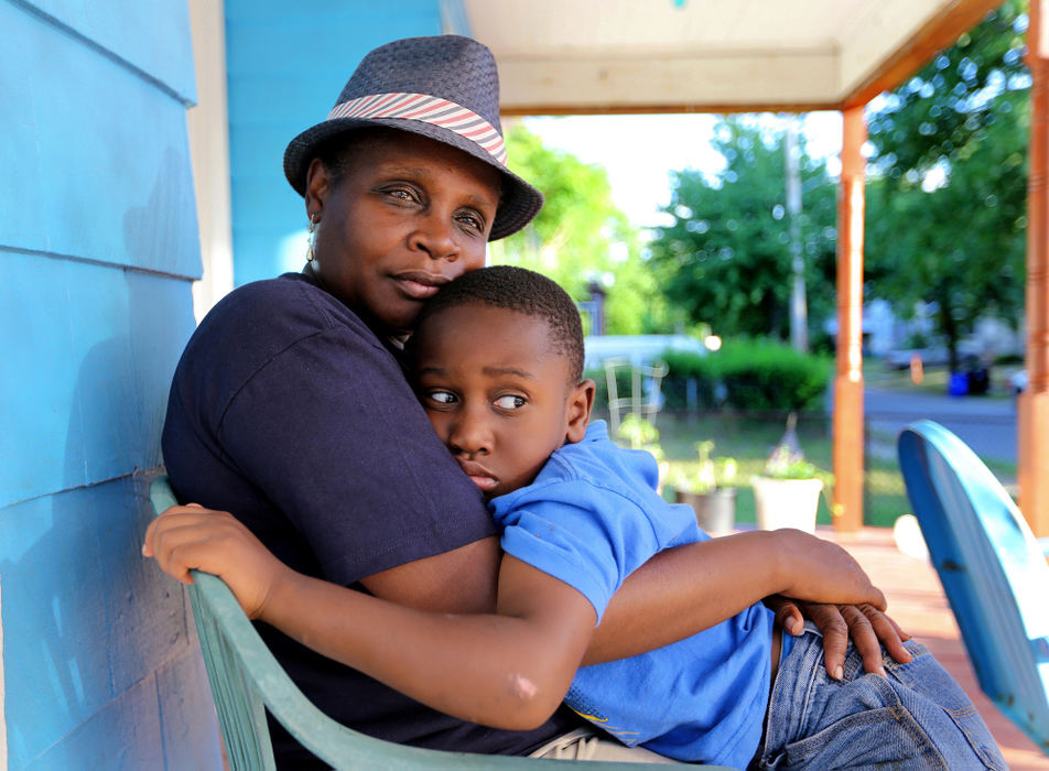 Award of Excellence, Ohio Understanding Award - Lisa DeJong  / The Plain DealerBernita Ashford, 57, hugs her grandson Carmelo Ashford, 5, at her home in the Hough neighborhood. Five generations of her family have lived in Hough. Ashford, a teacher, has lived in this home for 25 years. She grew up one street over. "This is the only place I wanted to come back and teach." The Ashford home is a gathering place for neighbors. "Everybody knows who we are, " Bernita Ashford said. Ashford organizes block parties and walks up to her church on the corner every day where she teaches summer camp. The Hough uprising in 1966 cemented Bernita Ashford’s devotion to the place that five generations of her family call home. Ashford remembers seeing National Guard tanks lined in front of her church. She and her siblings had to lay on the floor after hearing  bullets flying. Ashford mostly remembers the shirt that hung in her father William Ashford's armoire, the one he told them an errant bullet pierced but was stopped by a cigarette tin with a Bible inside. 