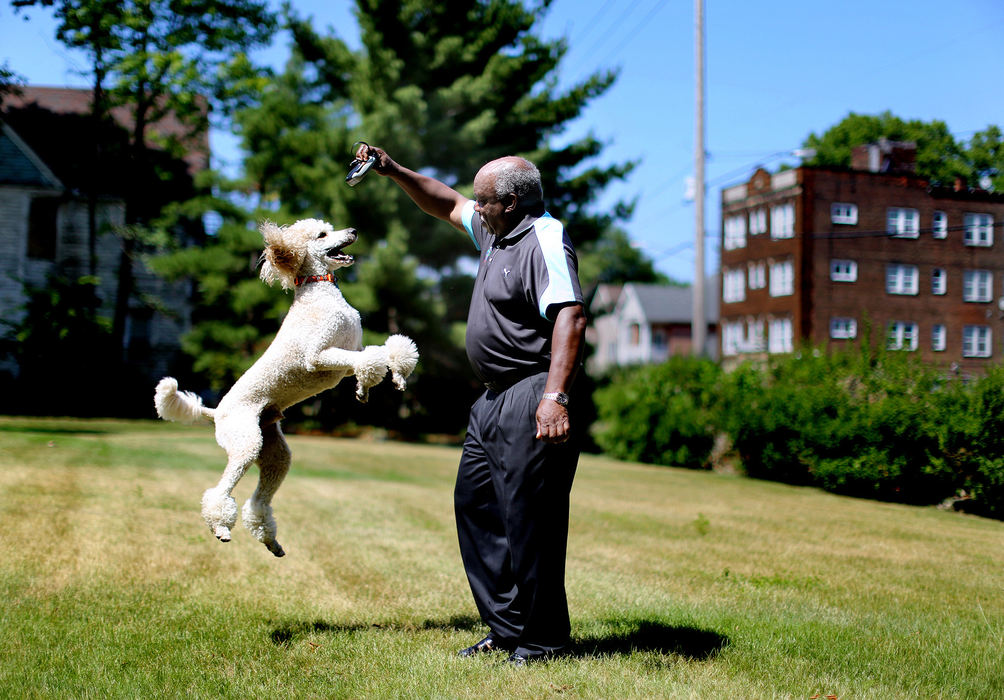 Award of Excellence, Ohio Understanding Award - Lisa DeJong  / The Plain DealerWilliam Tell, 69, a retired commander from the Cleveland Police Department, plays in his huge backyard with his Standard Poodle named "Cleveland" at his home in the Hough neighborhood. "At night time it's so quiet, it's best kept secret in town." Thirty years ago, when Tell first started talking about the dream house he was building on a series of empty lots on East 86th Street and Chester Avenue, some called him a fool. A fellow Cleveland police officer asked if he was going to put a moat with alligators around it. His gumption to build his dream home in the neighborhood where he was raised, spurred a flurry of single-family home construction in the late 1980s and early 1990s. 