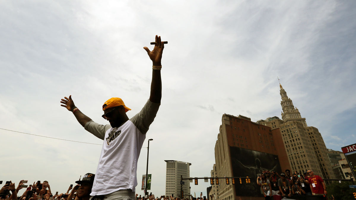 Award of Excellence, Photographer of the Year - Large Market - Gus Chan / The Plain DealerHolding a victory cigar in hand, LeBron James raises his arms to acknowledge the crowd while riding on Ontario St. during the Cleveland Cavaliers victory parade.  