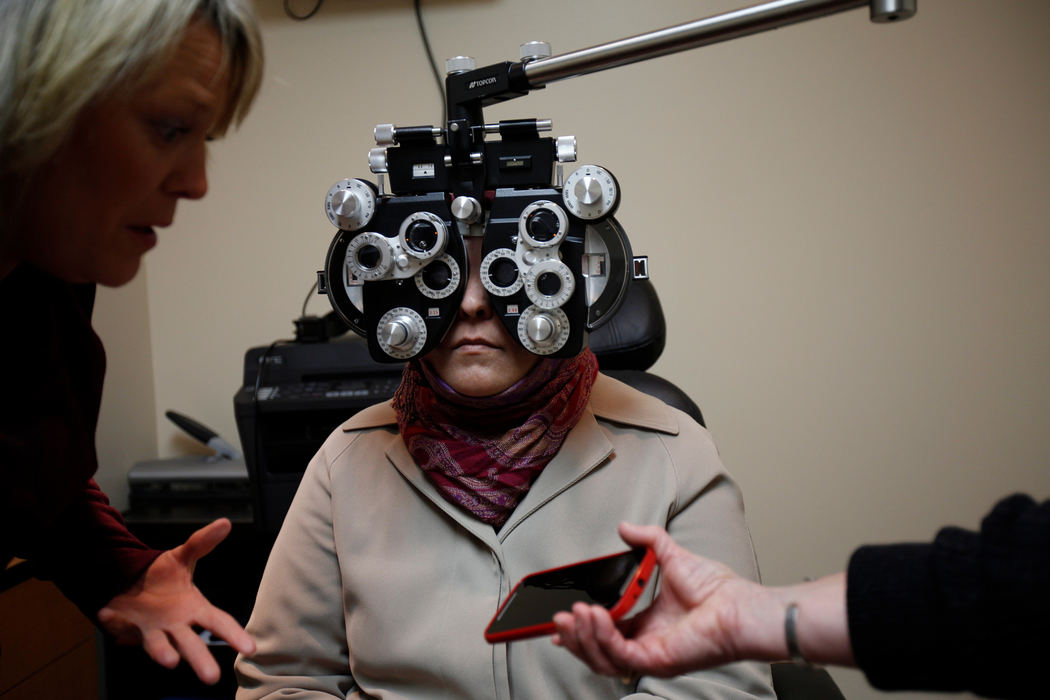 First Place, Photographer of the Year - Large Market -  / The Enquirer/Meg VogelKimberly Smith, OD, speaks to a translator on a phone that Therese Hazzard holds during Ahlam Alhamoud’s eye exam at Walmart in Evendale, Ohio Tuesday, March 22, 2016. Ahlam's glasses were held together with tape for the first five months she lived in Ohio. All the members of the family had to go through rigorous medical checks for the first few months they lived in Ohio. 