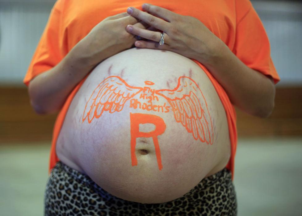 Second Place, Photographer of the Year - Large Market - Kyle Robertson / The Columbus Dispatch Telisha Clay, 18, said she will name her baby girl, who is due in May, after her cousin Hanna Rhoden.  Clay had her belly painted in remembrance of her slain family members. Hanna was with her 4-day-old baby when she was shot and killed while asleep.  The baby was unharmed.   Clay was at the park with family and friends to take part in the Pike County Vigil at the Pike County Fairgrounds in Piketon, Ohio on April 29, 2016.  
