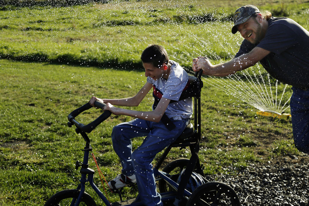 Second Place, Photographer of the Year - Large Market - Kyle Robertson / The Columbus Dispatch Rocky Grimes, right, helps push Michael Fuller, center, who has genetic chromosomal disorder drive a modified three-wheeled trike that helps Michaels range of motion  during a session on a farm in Mechanicsburg, Ohio on October 17, 2016.  Rocky runs Prescribed Power that develops equipment, programs, environments and strategies that make interactions between individuals of varying abilities and economic status mutually beneficial.  