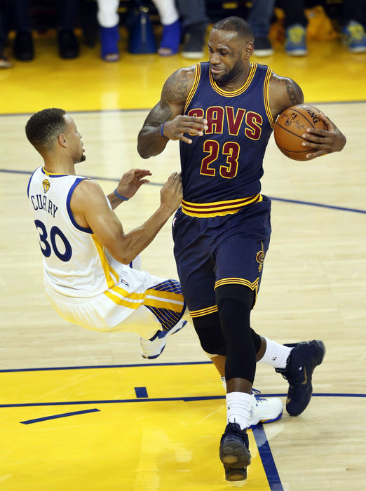 Second Place, Sports Picture Story - Gus Chan / The Plain DealerGolden State Warriors guard Stephen Curry falls as he tries to draw a charge from Cleveland Cavaliers forward LeBron James.