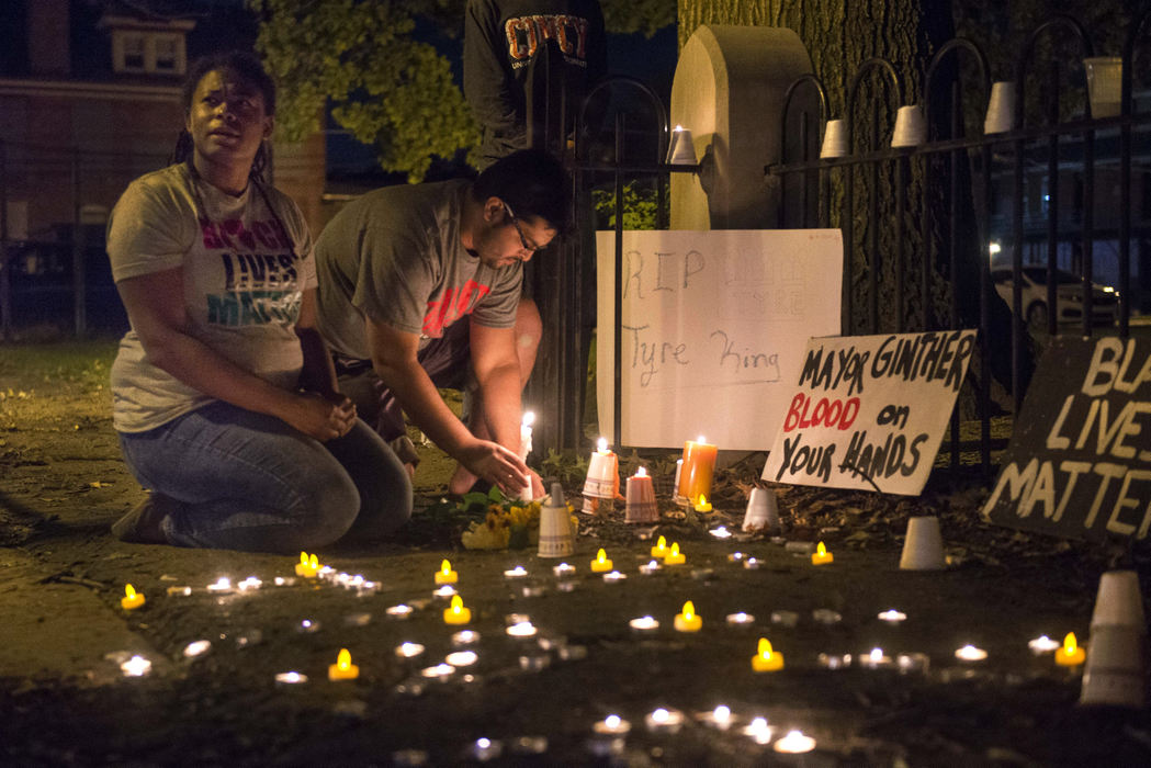 First Place, Team Picture Story -  / The Columbus Dispatch(From Left) Rachelle Dulan, of Columbus, and Ali Rizvi, of Columbus, relight candles at a shrine in memory of Tyre King near the intersection of S. 18th St. and Madison Ave. in Columbus on Sept. 15, 2016. King, 13,  was shot and killed by a Columbus police officer while holding a BB gun that closely resembled a real handgun. 
