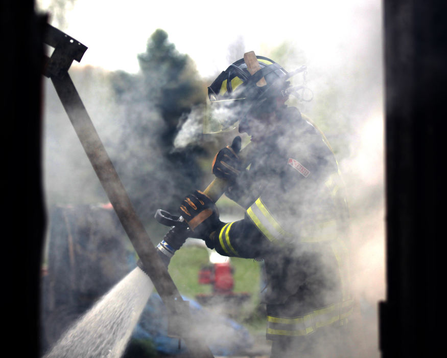 Spot News - 1st placeRome firefighter Kevin Squibbs hoses down the smoldering remnants of a  garage and work area at 1747 Lenox - New Lyme Road in Lenox Township. (William A. West / Wwest News Service)