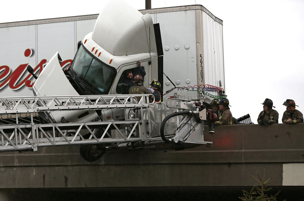 Spot News - 1st place - A truck driver is pulled out of cab by Columbus fire fighters as it dangles on the edge of the state route 315 north-bound bridge over Sullivant Avenue on the West Side of Columbus. The north-bound lanes of 315 had to be closed as emergency responders worked to save the driver of a crashed semi trailer.  (Eamon Queeney / The Columbus Dispatch)