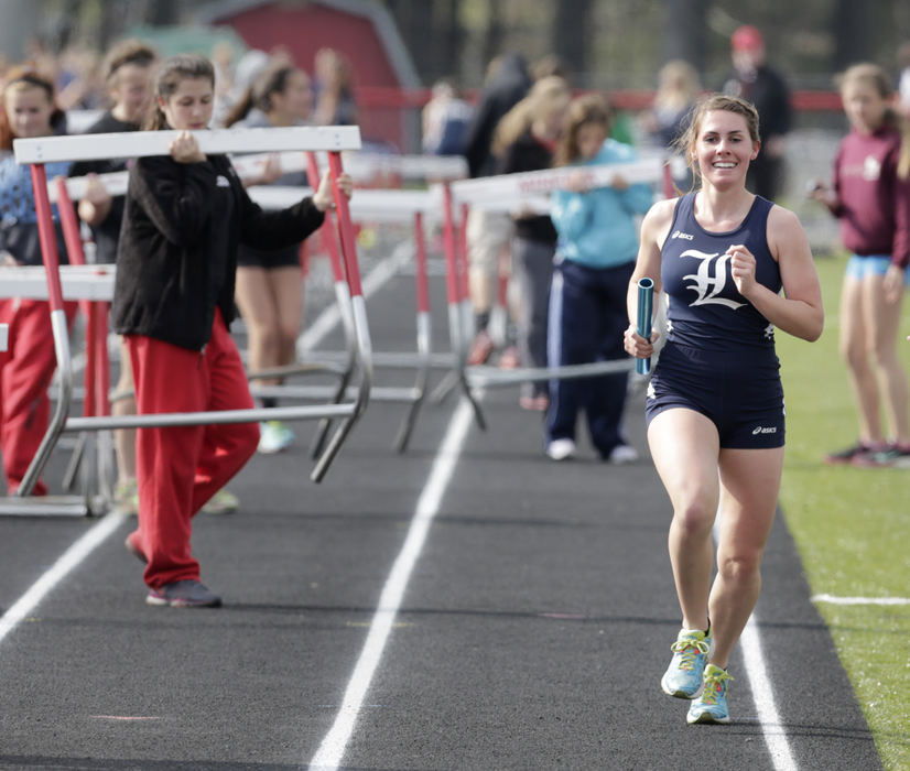 Sports - 2nd place - Haley Bradley of Louisville reacts as she approaches the finish line in first place as the anchor of the 4x800 relay. The hurdle crew had already begun to set up for the next event as the relay concluded prompting the PA announcer to announce that there was one more runner on the track. The boys and girls ran a combined 4x800 event for the duel meet at Minerva. (Scott Heckel / The (Canton) Repository)