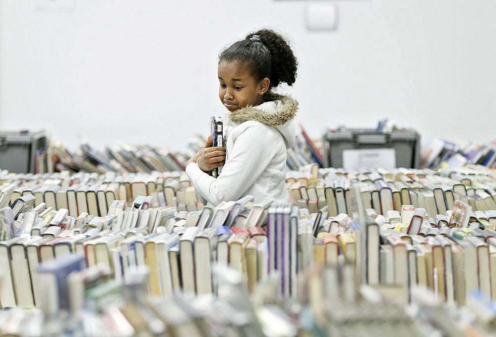 Feature -1st place - Safia Guled of Gahnna browses the stacks while shopping with her family at the annual Big Book Sale hosted by The Friends of the Columbus Metropolitan Library. (Barbara J. Perenic / The Columbus Dispatch)