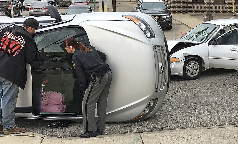 Spot News - 1st place - A Clark County Sheriff's deputy and an unidentified man try to comfort a woman who was trapped in her car when it rolled following an two vehicle accident. The driver of the white car, in the background, and the woman where transported to the hospital with non-life threatening injuries.  (Bill Lackey / Springfield News-Sun)