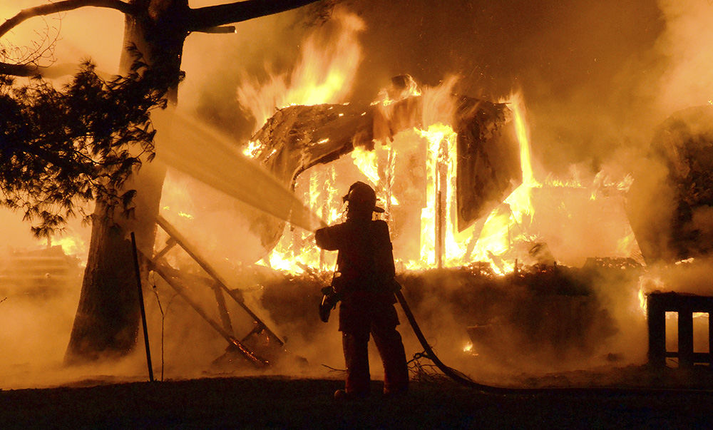 Spot News - 2nd place - A Lisbon firefighter throws water on a burning trailer at the Threshing Floor Campgrounds and Chapel. No one was injured, but five people are homeless after two 12- by 60- foot mobile homes at the Threshing Floor Campgrounds and Chapel burned to the ground. (Patricia Schaeffer / The (Lisbon) Morning Journal)