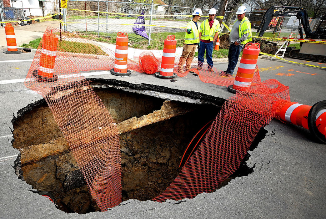 Spot News - 2nd placeWorkers look down a sinkhole that has closed North Detroit Avenue at Fernwood Avenue in Toledo. (Kurt Steiss/The Blade)