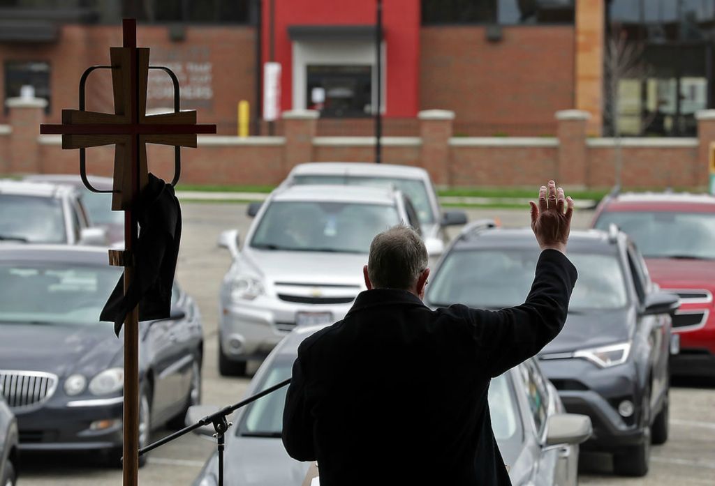 General News - HM - The Reverend John Pollock, pastor of St. John's Lutheran Church, presides over the Good Friday service in the parking lot of the church. Parishioners lined their cars up and stayed inside them with their window open to hear Pollock's sermon. The church will have a similar service on Easter Sunday.  Bill Lackey / Springfield News-Sun