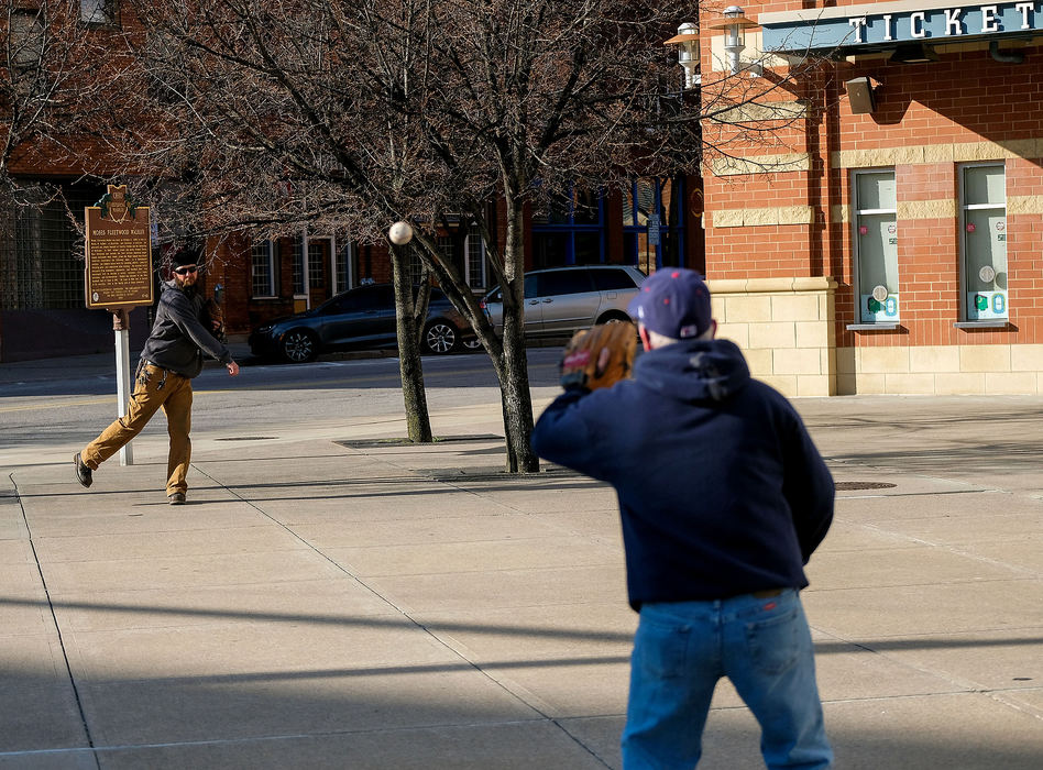 Sports Feature - HM - Gabriel Huth (left) and his father, Jerry Huth, both of Toledo, throw a baseball outside Fifth Third Field in Toledo on what would have been the opening day for the Mud Hens had COVID-19 not postponed the start of the Minor League Baseball season. "We were at the first opening game downtown, and then I don't think we've missed one since," Jerry said.   Kurt Steiss / The Blade