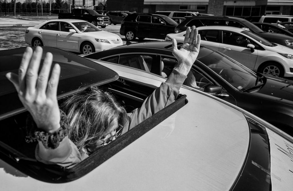 Story - 1st place - Peggy Goetz, a nurse at Mercy Health, prays for health care workers to stay safe amid the COVID-19 pandemic during a "park and pray" from a parking lot that faces Mercy Health - St. Vincent Medical Center in Toledo. Jeremy Wadsworth / The Blade