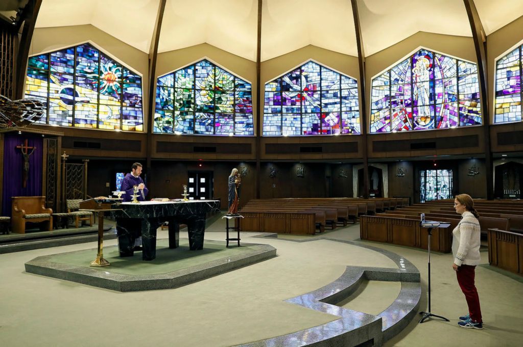 Story - HM - Daniella Weddle records Father David Schalk during a Spanish service for his parishioners in an empty Christ the King Catholic Church in Columbus The church would have around 75 parishioners at Friday evenings services.   Kyle Robertson / Kyle Robertson