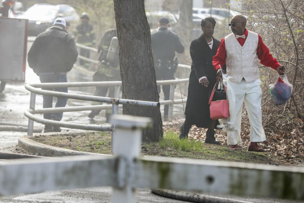 Spot News - 1st place - Toledo residents Tashia McNeirr (left) and James McNair avoid emergency vehicles and first responders battling an apartment fire while making their way to an Easter service at Briar Cliff Woods apartments in Toledo.  (Isaac Ritchey / The Blade)