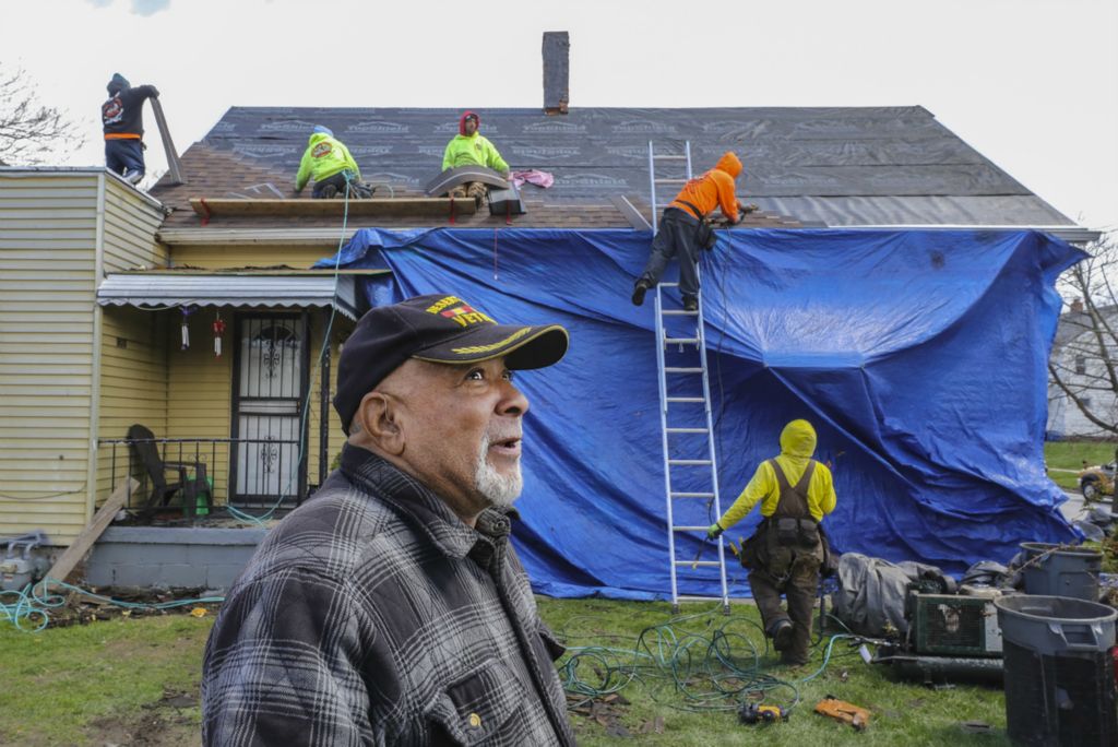 General News - 1st place - Veteran Glenn Walker stood in his front yard  and watched as a roofing crew layered rows of new brown asphalt shingles on top of his 124-year-old North Toledo home."I'm feeling good, I'm feeling good," said Mr. Walker, 69, the remnants of the old roof strewn around him. "You know how long it's taken me to get this. ... It's a blessing." Mr. Walker and his wife, Sheila, struggled a long time to figure out how to get a new roof. They dreaded big rainstorms, which would often trigger multiple leaks inside their small yellow home on St. John Avenue. Mr. Walker got his new roof installed with aid of the Lucas County Veterans Service Commission in Toledo.  (Jeremy Wadsworth / The Blade)