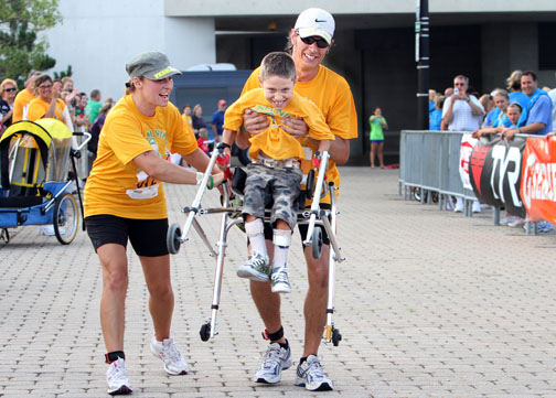 General News - HM - Six year old  Niko Lanzarotta, the namesake of Team Niko, gets an assist to the finish line from his mom, Kasia (left) and dad, Mike, at the 25th anniversary running of the Cleveland Triathlon. Niko rode in a trailer for the bicycle portion of the race, and in a push cart for the running portion until they neared the finish line, when he got out of the stroller, grabbed on to his walker and raced to the finish.  (Lynn Ischay  / The Plain Dealer)