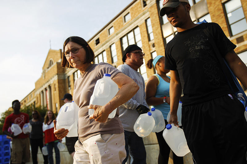 General News - 3rd place - Kathy Wielfaert, (left) of West Toledo, walks away with two two gallon jugs of water in her arms at Central Catholic High School in Toledo. (Isaac Hale / The (Toledo) Blade)