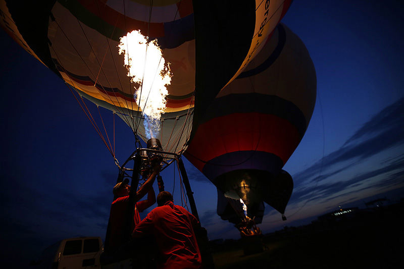 General News - 3rd place - Pilot John Petrehn (left) and crew chief Sam Clegg, both of Houston, fill the Touchstone Energy balloon with hot air as it begins to rise for the balloon glow during the 40th annual All Ohio Balloon Fest at the Union County Airport in Marysville. (Eamon Queeney / The Columbus Dispatch)