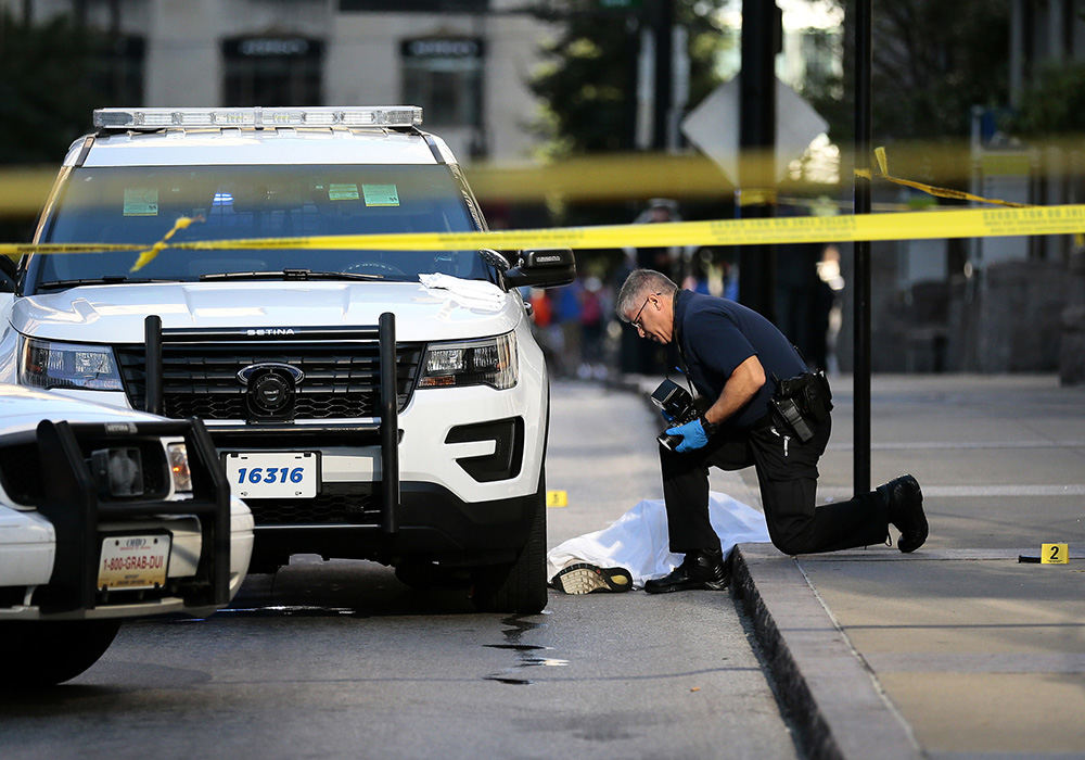 ASpot News - 2nd place - A crime scene investigator takes photographs where the body of a man shot by police remains at the scene of a police involved shooting near the intersection of East 5th and Main Streets in downtown Cincinnati . The area around downtown's Government Square was blocked off to traffic as investigators examined the scene. (Sam Greene / Cincinnati Enquirer)