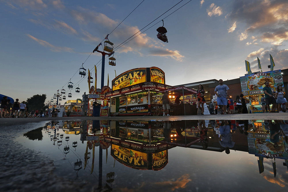 Story - 3rd place - Rides and concessions are reflected in a puddle at the Ohio State Fair. (Tom Dodge / The Columbus Dispatch)