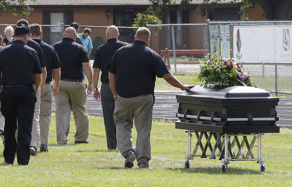 General News - 1st place - One of the Greenon High School football coaches touches Connor Williams' casket as the coaches walk off the field after speaking during a joint funeral for student athletes Connor and David Waag at school's football stadium. The two were killed in a car accident. (Bill Lackey/Staff / Springfield News-Sun)