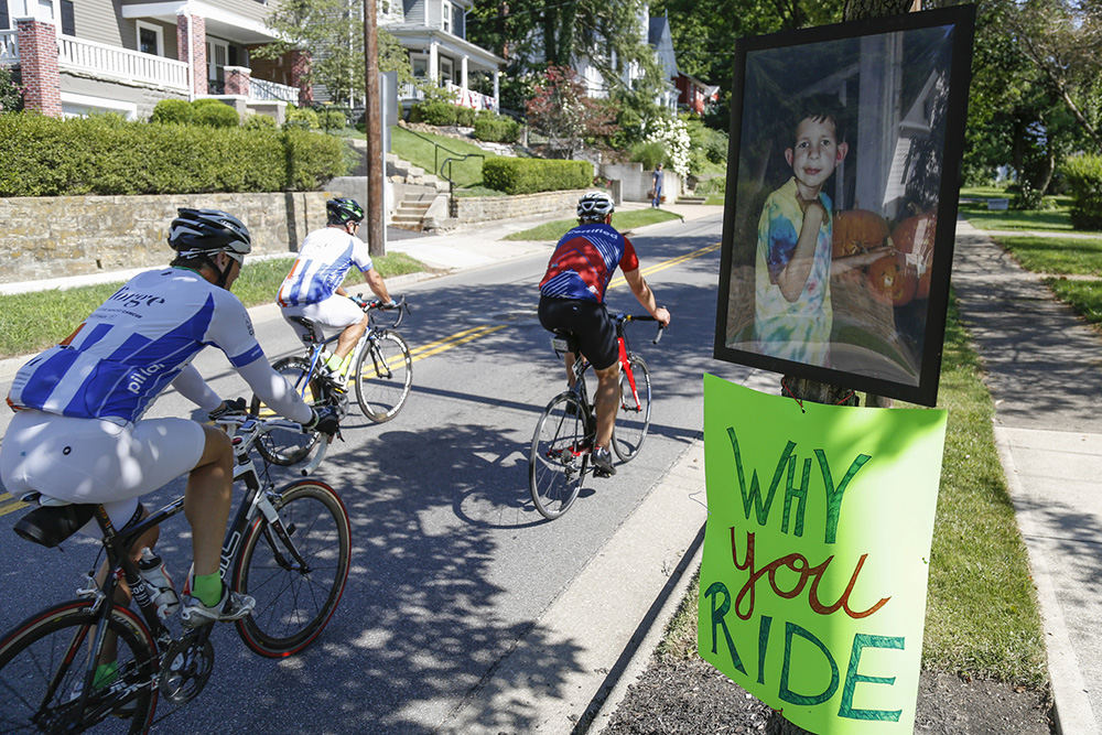 MTStory - 1st place - A photograph of Brandon Reyes sits outside his family's home as riders head up North Pearl Street during Pelotonia 2017 in Granville. Reyes died in 2008 at 16-years-old after battling a brain tumor. (Joshua A. Bickel / The Columbus Dispatch)